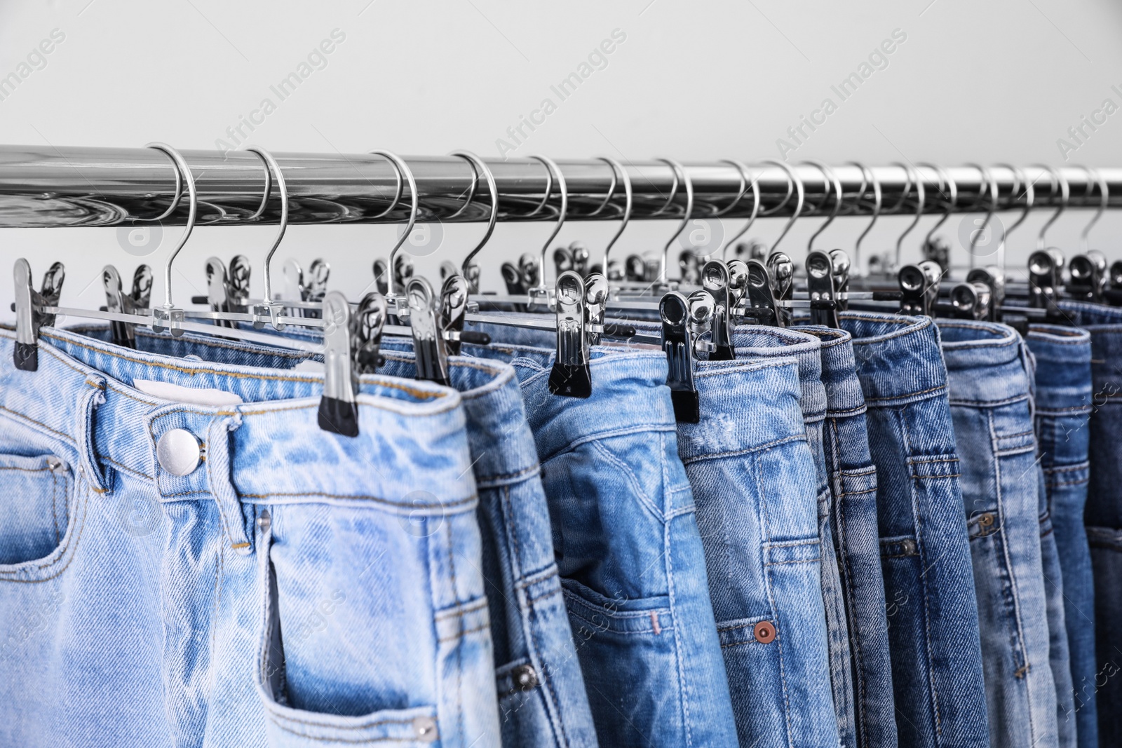 Photo of Rack with different jeans on light background, closeup