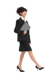 Beautiful businesswoman with laptop walking on white background