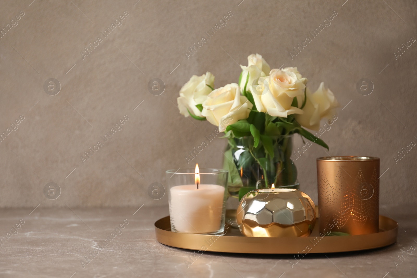 Photo of Tray with burning wax candles and flowers on table