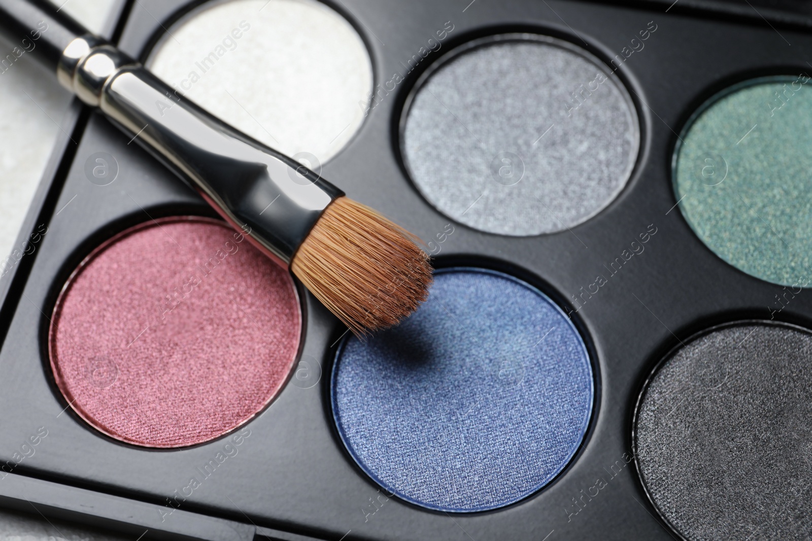 Photo of Beautiful eye shadow palette and brush on grey table, closeup