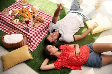 Photo of Happy couple imitating picnic at home, above view