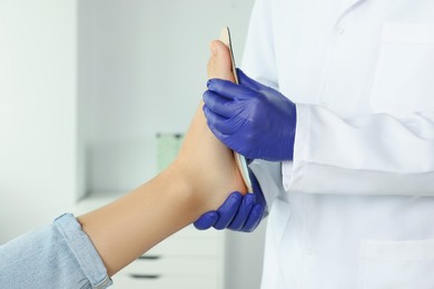 Photo of Male orthopedist fitting insole to patient's foot in hospital, closeup