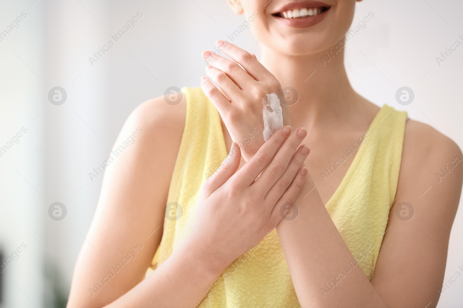 Photo of Young woman applying hand cream at home, closeup