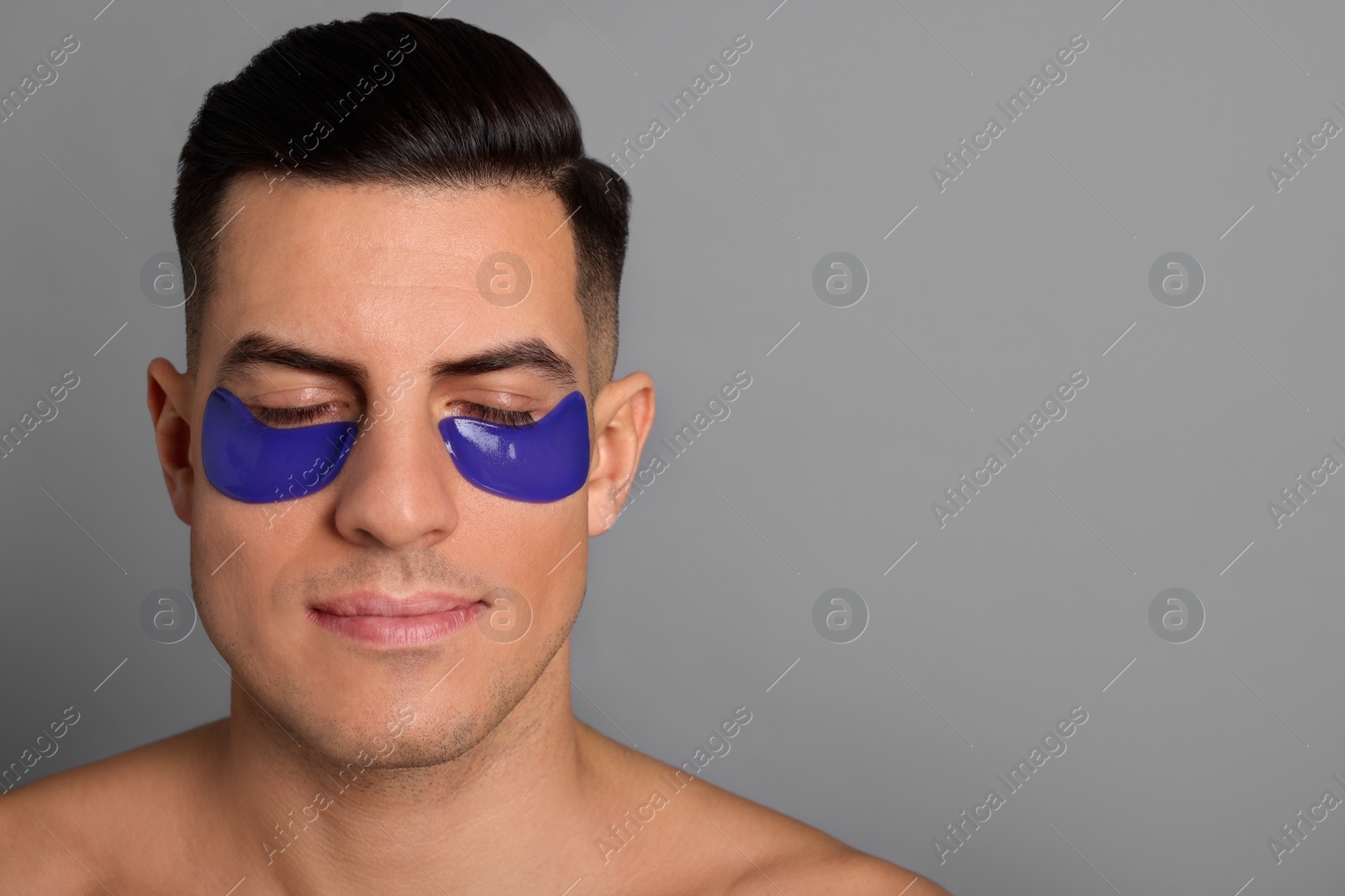 Photo of Man with blue under eye patches on grey background. Space for text