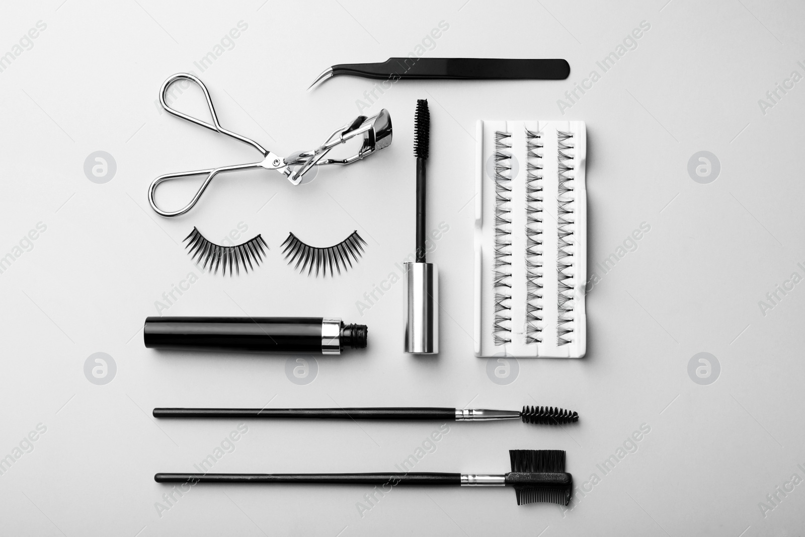 Photo of Artificial eyelashes and accessories on grey background, flat lay