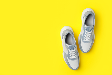 Photo of Stylish sneakers on yellow background, flat lay. Space for text