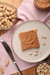 Photo of Toast with tasty nut butter and peanuts on wooden table, flat lay