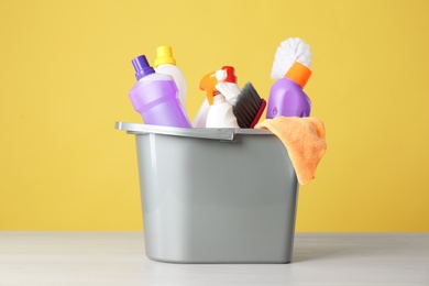 Photo of Bucket with cleaning products and tools on grey table