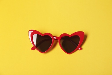 Photo of Stylish heart shaped glasses on color background, top view