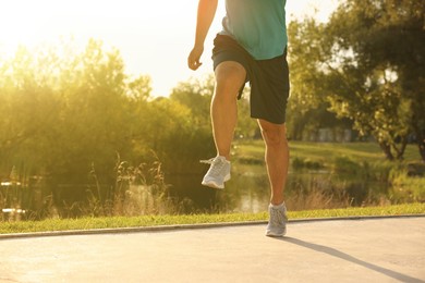 Photo of Man running near pond in park, closeup. Space for text