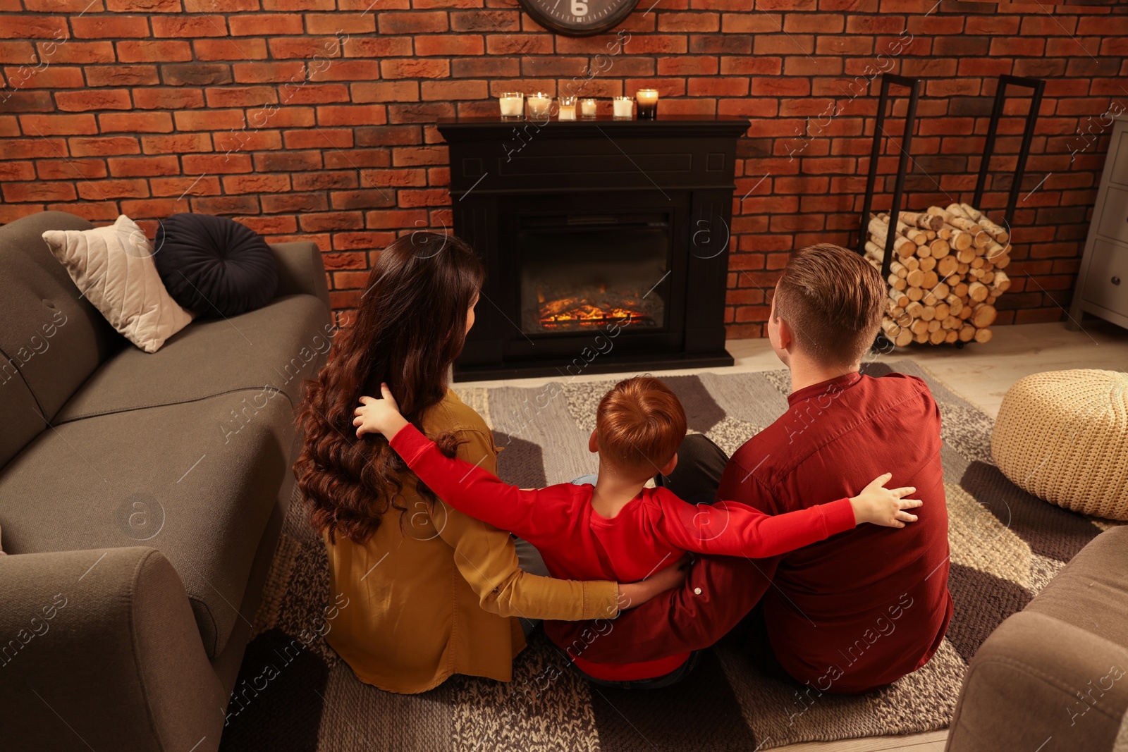 Photo of Happy family spending time together on floor near fireplace at home, back view