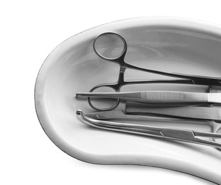 Surgical instruments in kidney dish on white background, top view
