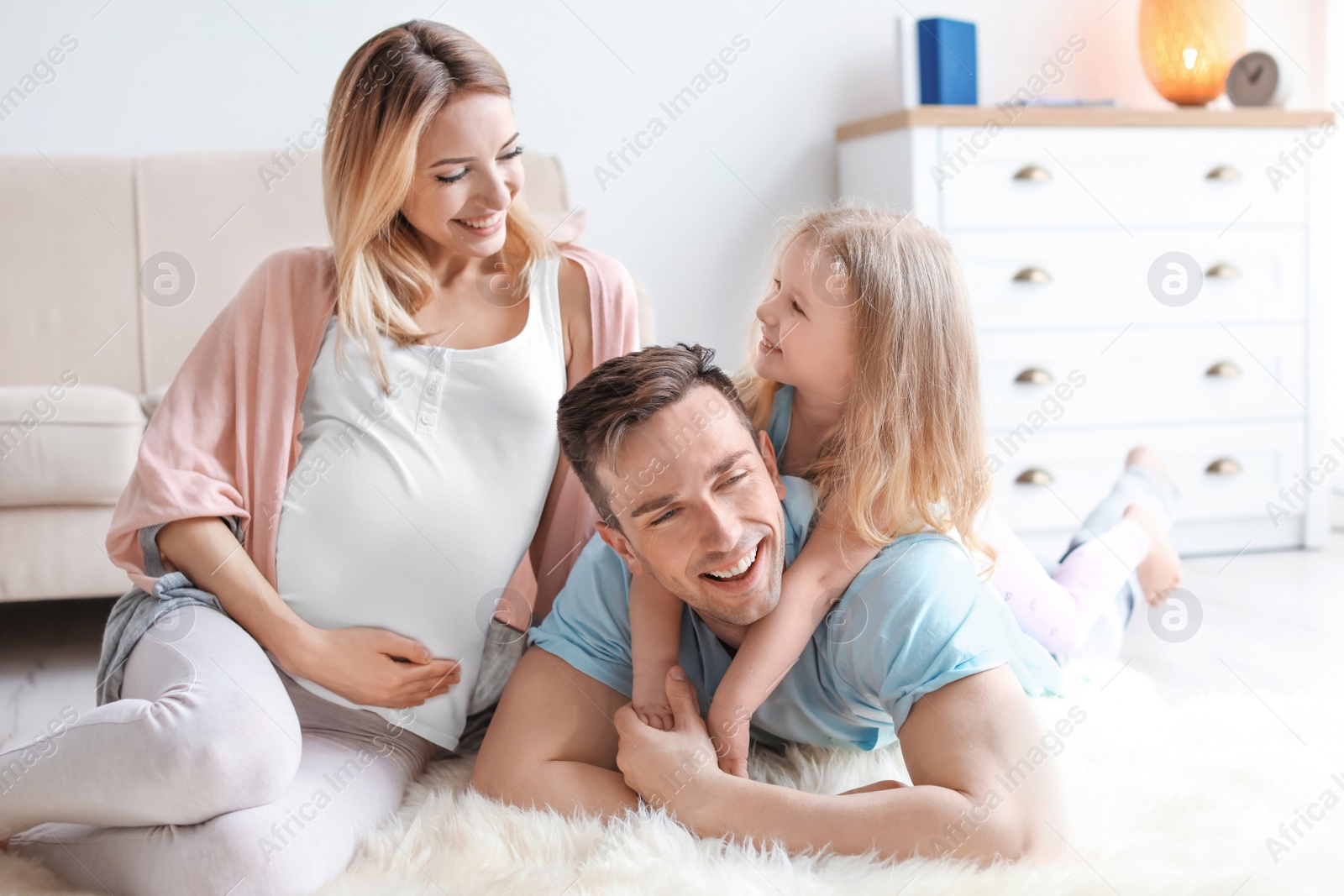 Photo of Young pregnant woman with her family at home