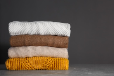 Photo of Stack of folded knitted sweaters on grey background