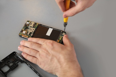 Technician repairing mobile phone at table, closeup