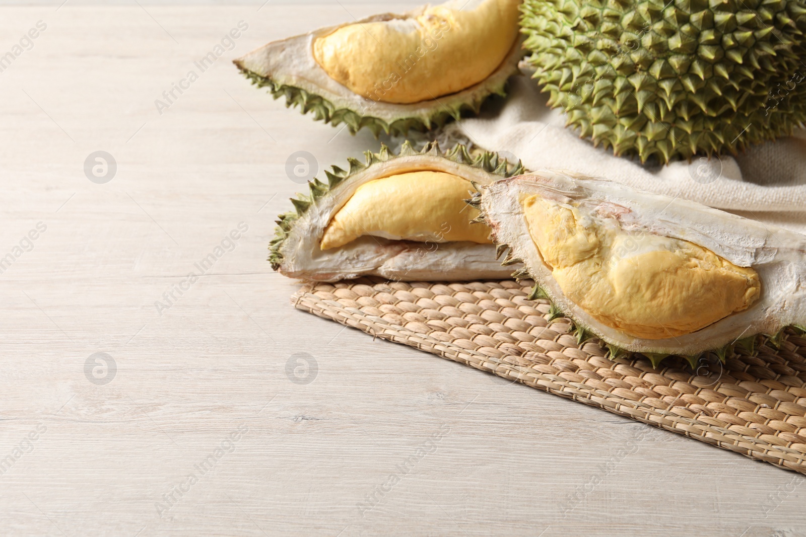 Photo of Fresh ripe durians on light wooden table. Space for text