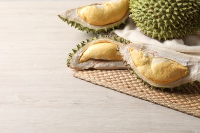Photo of Fresh ripe durians on light wooden table. Space for text