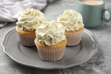 Tasty cupcakes with vanilla cream on grey table, closeup