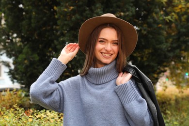 Photo of Beautiful young woman wearing stylish clothes in autumn park