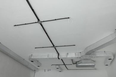 Black cables and ventilation system on white ceiling