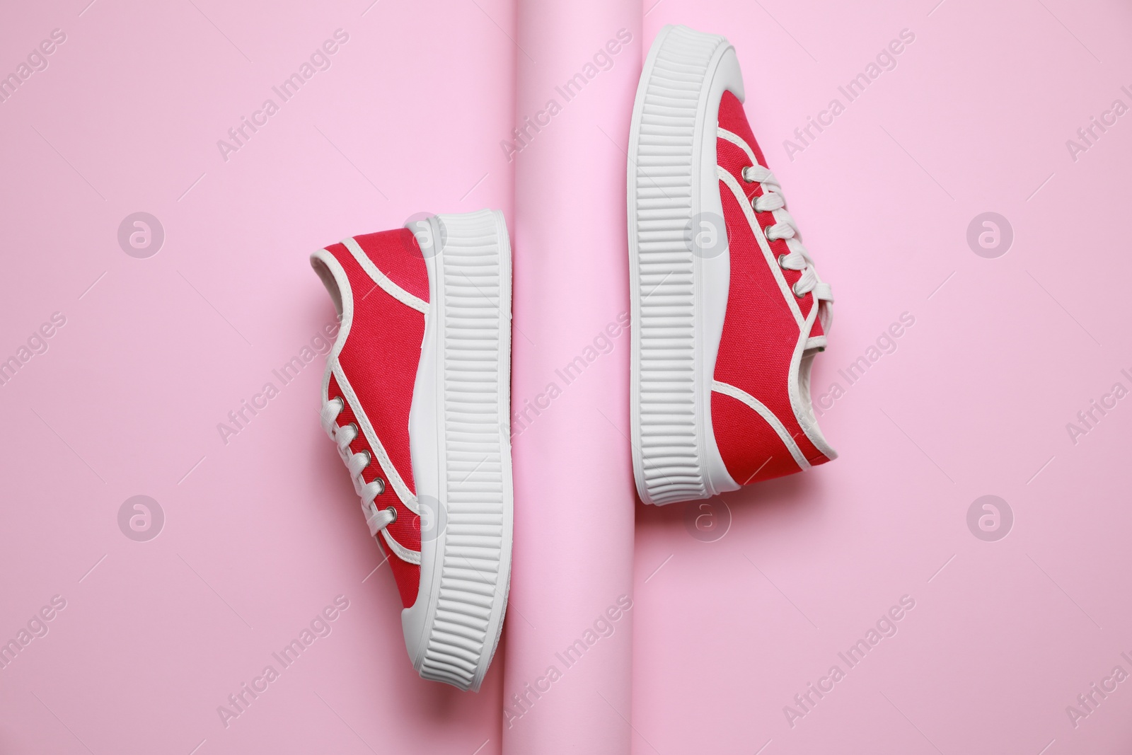 Photo of Stylish presentation of red classic old school sneakers on pink background, flat lay