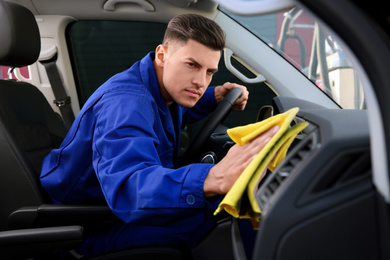 Car wash worker cleaning modern automobile interior