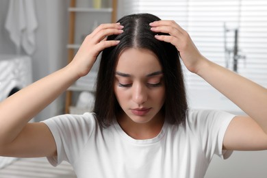 Photo of Woman examining her hair and scalp at home. Dandruff problem