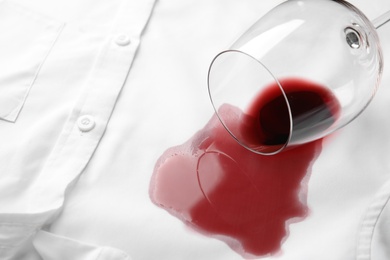 Photo of Overturned glass and spilled exquisite red wine on white shirt. Space for text