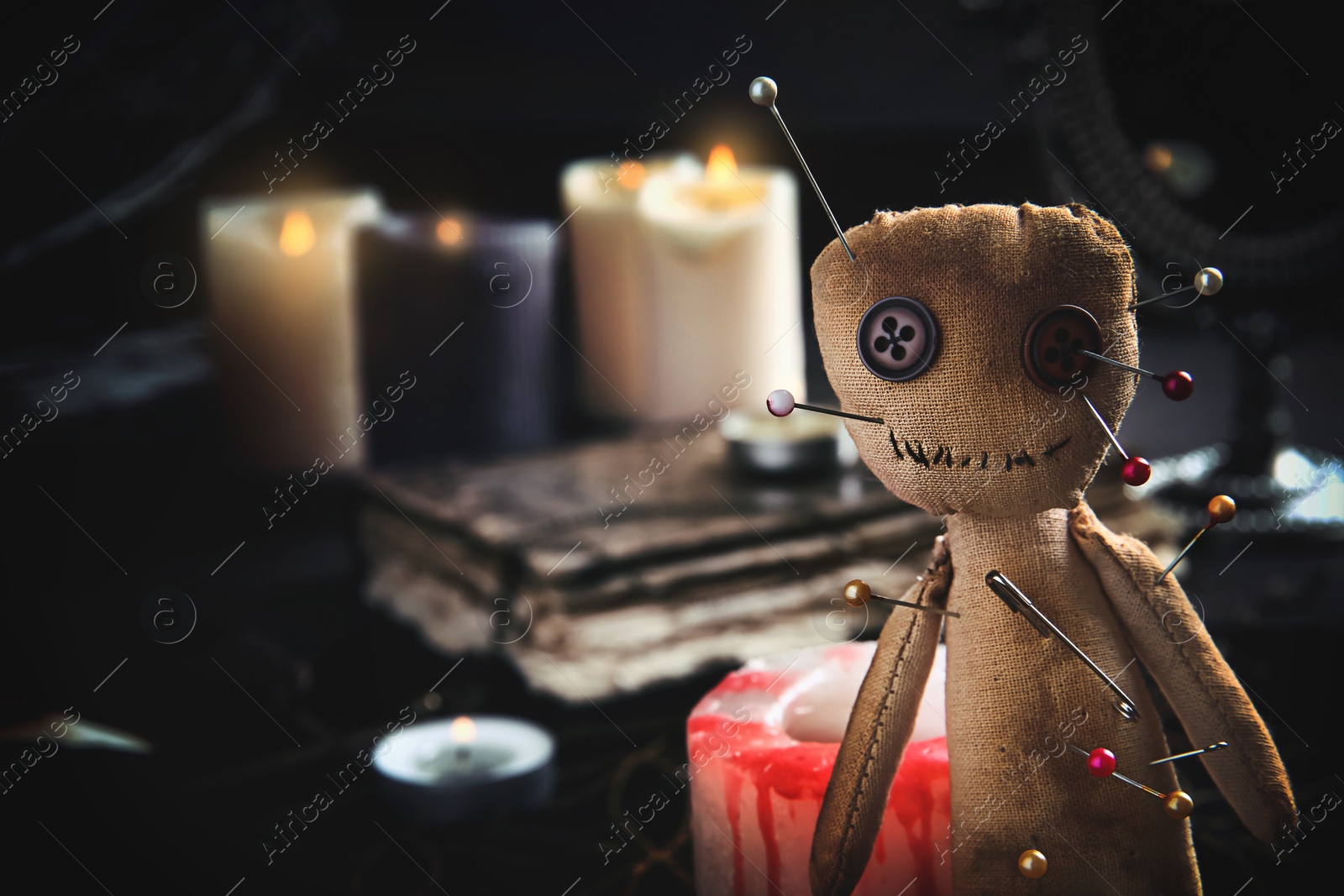Image of Voodoo doll pierced with pins on table indoors, closeup