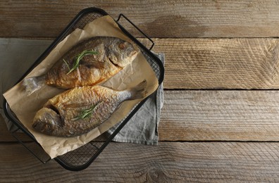 Photo of Delicious dorado fish with rosemary on wooden table, top view. Space for text