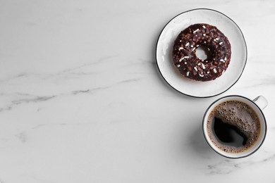 Photo of Tasty donut and cup of coffee on white marble table, flat lay. Space for text