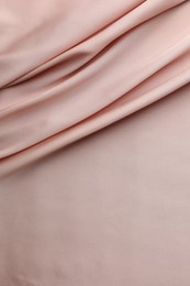 Photo of Crumpled pink silk fabric as background, top view. Space for text