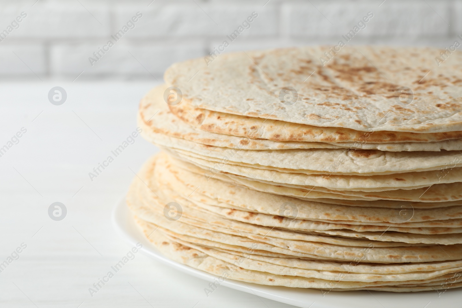 Photo of Stack of tasty homemade tortillas on white table