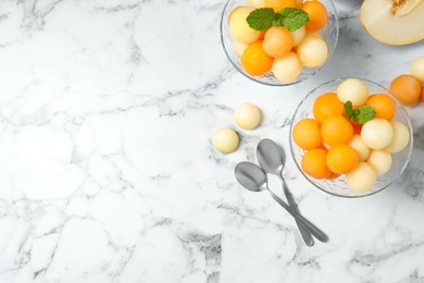 Photo of Flat lay composition with melon balls and mint on white marble table, space for text