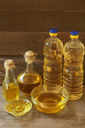 Photo of Bottles and glass bowls with sunflower oil on wooden table