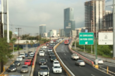 Photo of Blurred view of asphalt highway with cars and buildings in city