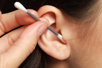 Photo of Woman cleaning ear with cotton swab, closeup