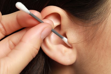 Woman cleaning ear with cotton swab, closeup