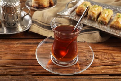 Photo of Glass of traditional Turkish tea and sweets served in vintage tea set on wooden table