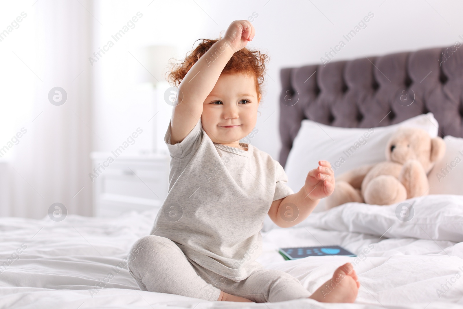 Photo of Cute little child sitting on bed at home