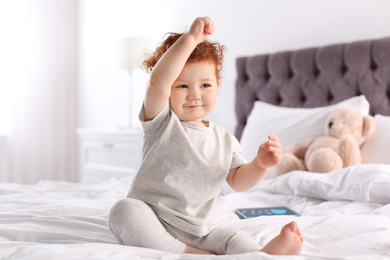 Cute little child sitting on bed at home