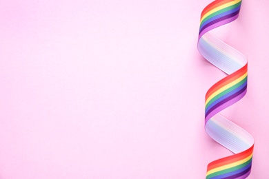 Top view of rainbow ribbon on pink background, space for text. Gay symbol