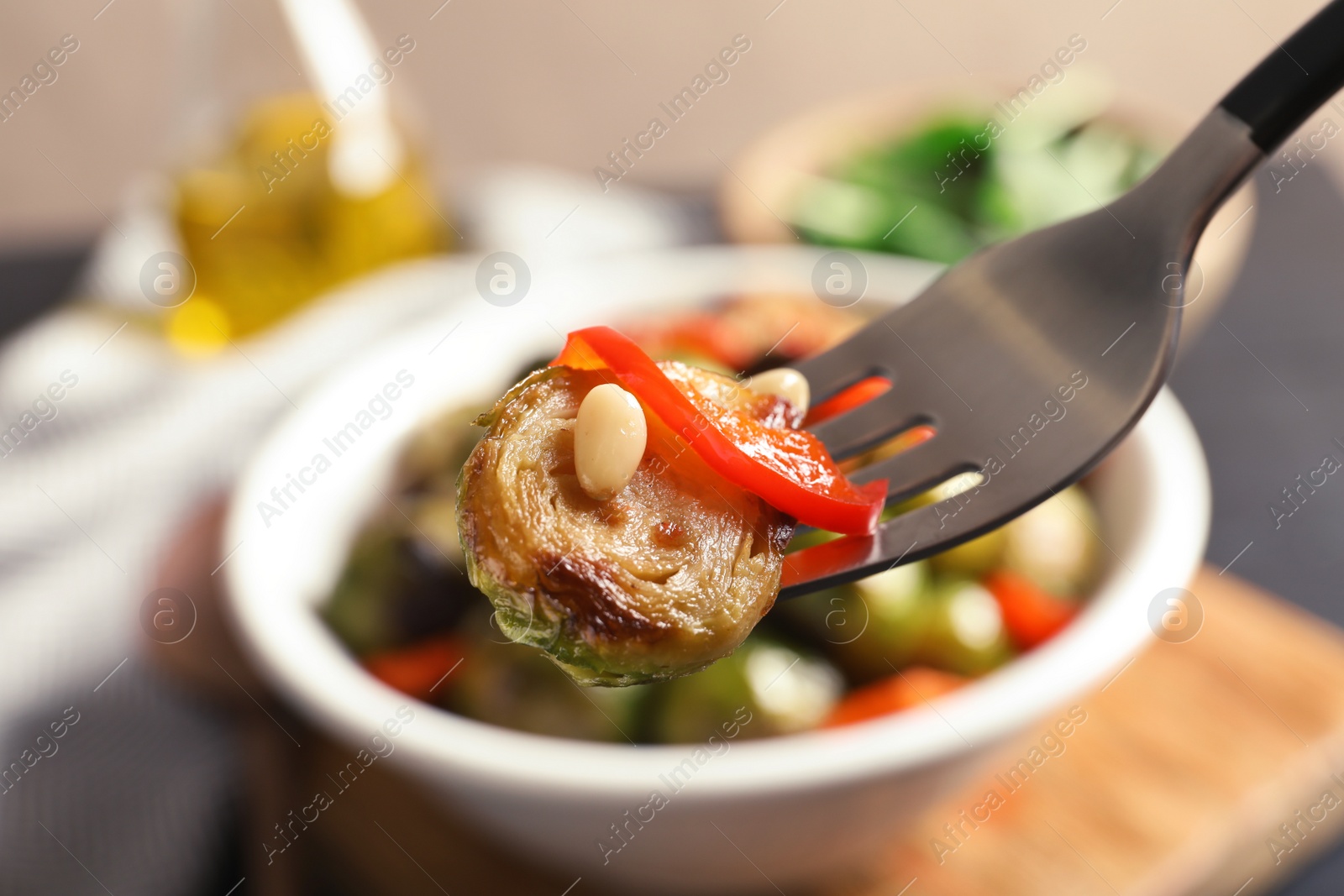 Photo of Fork with warm Brussels sprouts salad over table, closeup