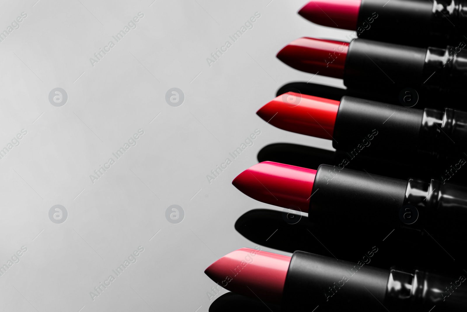 Photo of Many bright lipsticks on light grey background, space for text