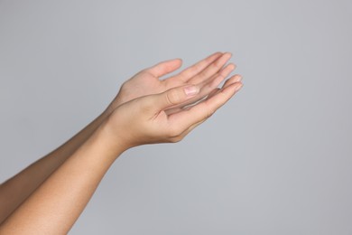 Photo of Woman stretching hands against light grey background, closeup. Space for text