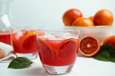 Photo of Tasty sicilian orange juice with ice cubes and fruits on white table