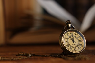 Photo of Pocket clock with chain on wooden table, closeup. Space for text