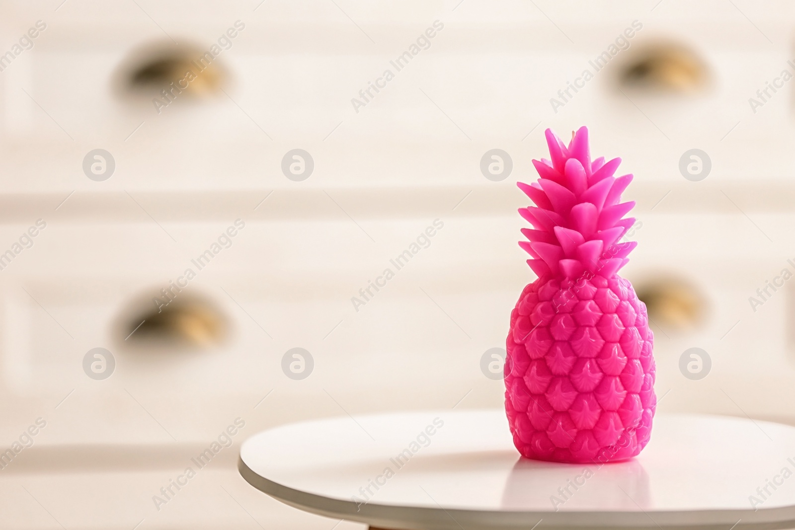 Photo of Stylish pineapple candle on table. Home decorating idea