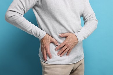 Photo of Arthritis symptoms. Man suffering from hip joint pain on light blue background, closeup