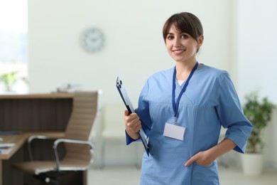 Photo of Portrait of smiling medical assistant with clipboard and pen in hospital. Space for text